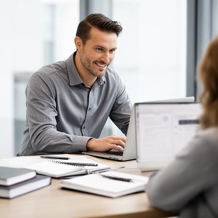 Owen Marlowe, Head of Customer Success, helping a client on a laptop at a desk with notebooks